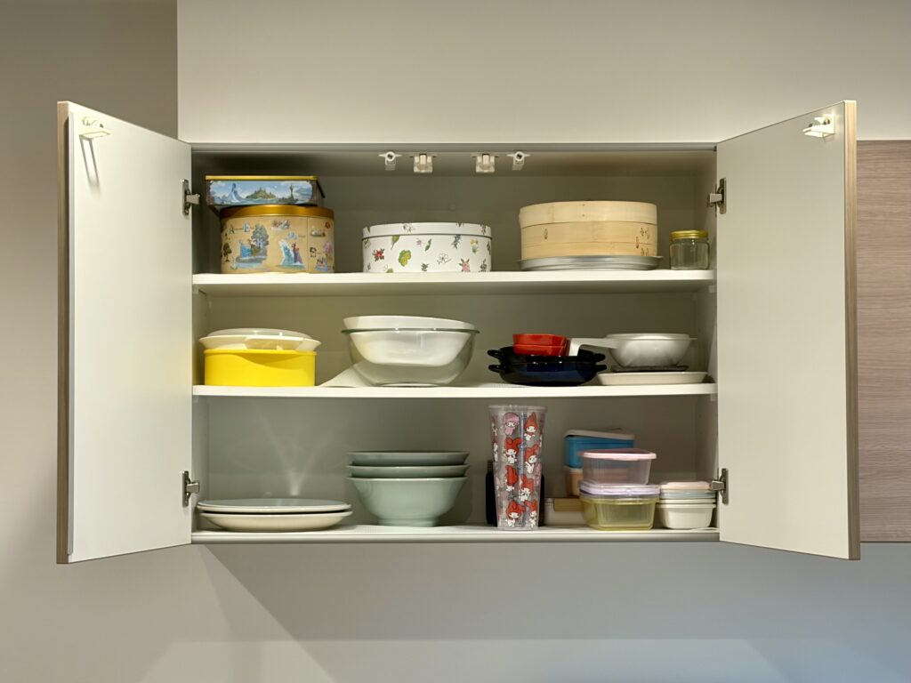 扉を開けたウォールキャビネットの内部。可動棚2枚で3段に分け、食器や保存容器を収納している様子